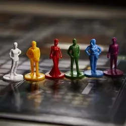 Gros plan sur les pions de personnages et les 6 armes miniatures du jeu Cluedo