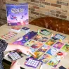 Vue d ensemble du plateau de jeu Stella Dixit Universe avec la grille de cartes et les ardoises effacables